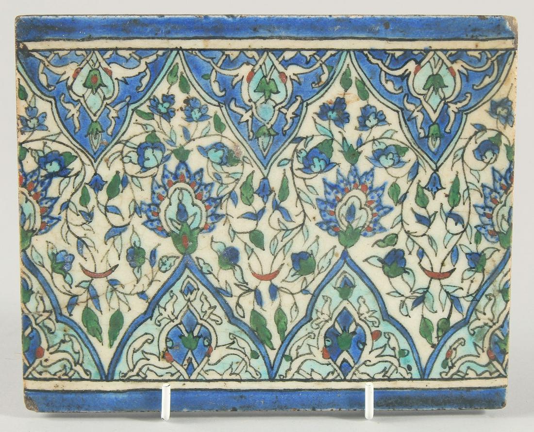 A 18TH/19TH CENTURY IZNIK GLAZED POTTERY TILE, decorated with foliate motifs in blue, turquoise and: A 18TH/19TH CENTURY IZNIK GLAZED POTTERY TILE, decorated with foliate motifs in blue, turquoise and red, 16cm x 20cm.