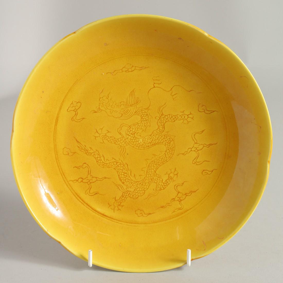A CHINESE YELLOW GLAZE PORCELAIN DRAGON DISH, with petal form rim and incised dragon to the centre,: A CHINESE YELLOW GLAZE PORCELAIN DRAGON DISH, with petal form rim and incised dragon to the centre, six-character mark to base, 22cm diameter.