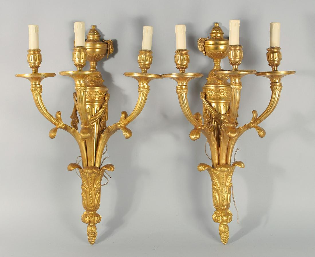 A LARGE PAIR OF LOUIS XVITH STYLE GILT METAL THREE LIGHT WALL SCONCES with urn finials. 25ins long. (1 of 1)