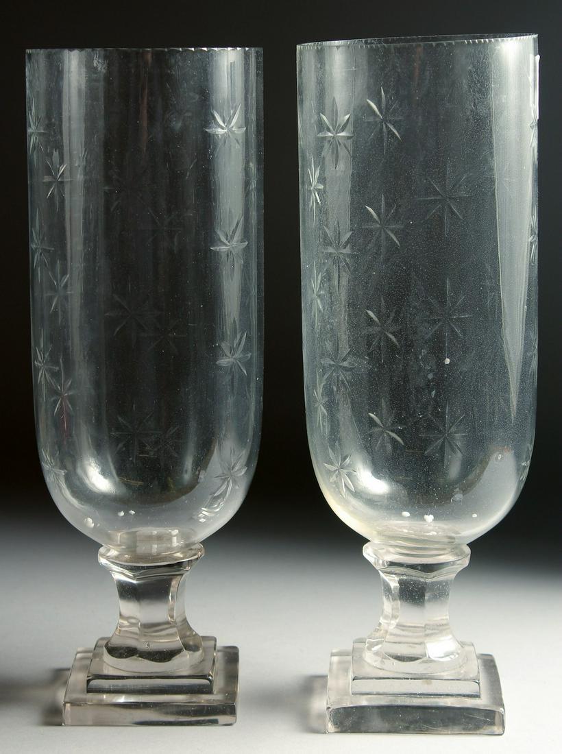 A SMALL PAIR OF GLASS STORM - HURRICANE LAMPS on square bases. 13ins high.: A SMALL PAIR OF GLASS STORM - HURRICANE LAMPS on square bases. 13ins high.