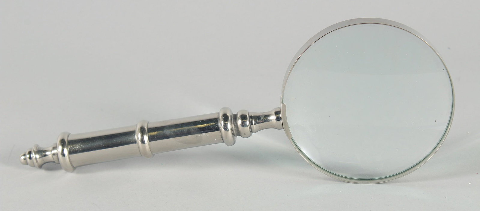 A MAGNIFYING GLASS with a chrome handle.: A MAGNIFYING GLASS with a chrome handle.
