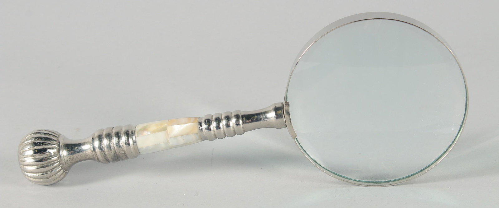 A MAGNIFYING GLASS with a chrome and mother of pearl handle.: A MAGNIFYING GLASS with a chrome and mother of pearl handle.