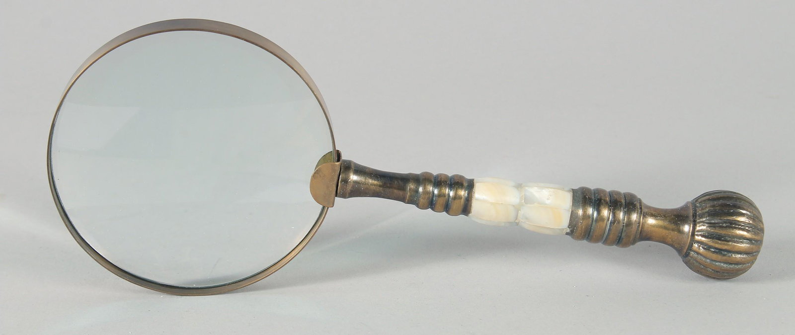 A MAGNIFYING GLASS with a chrome and brass handle.: A MAGNIFYING GLASS with a chrome and brass handle.