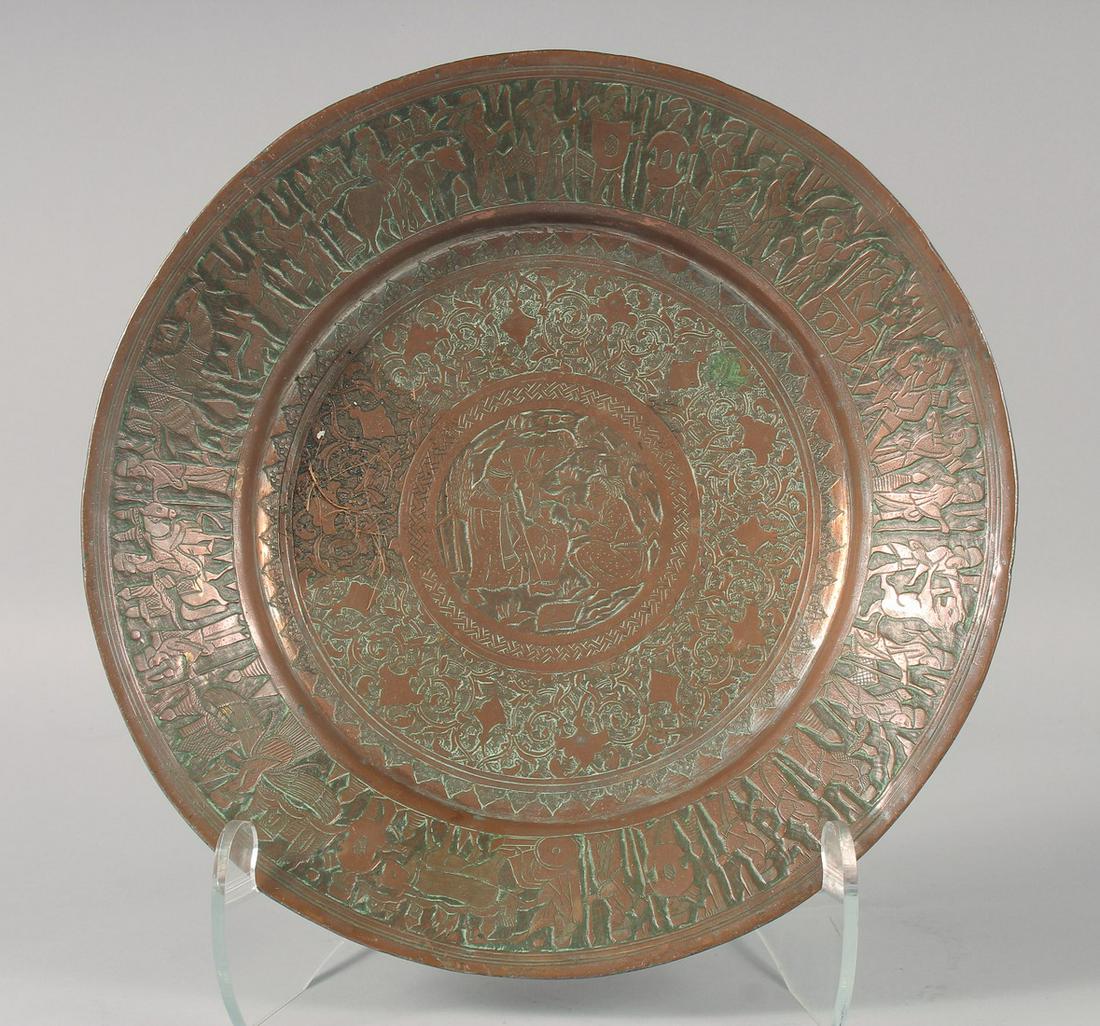 AN ISLAMIC TINNED COPPER CHARGER, with engraved and chased decoration depicting figures, 33.5cm: AN ISLAMIC TINNED COPPER CHARGER, with engraved and chased decoration depicting figures, 33.5cm diameter.