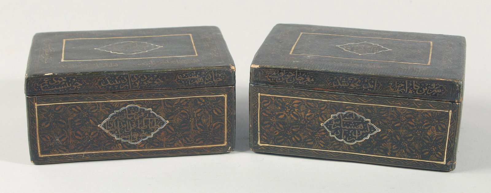A PAIR OF EARLY 19TH CENTURY PERSIAN QAJAR SIGNED LACQUERED PAPIER-MACHE BOXES, with bands and: A PAIR OF EARLY 19TH CENTURY PERSIAN QAJAR SIGNED LACQUERED PAPIER-MACHE BOXES, with bands and panels of calligraphy, each 16.5cm x 11cm.