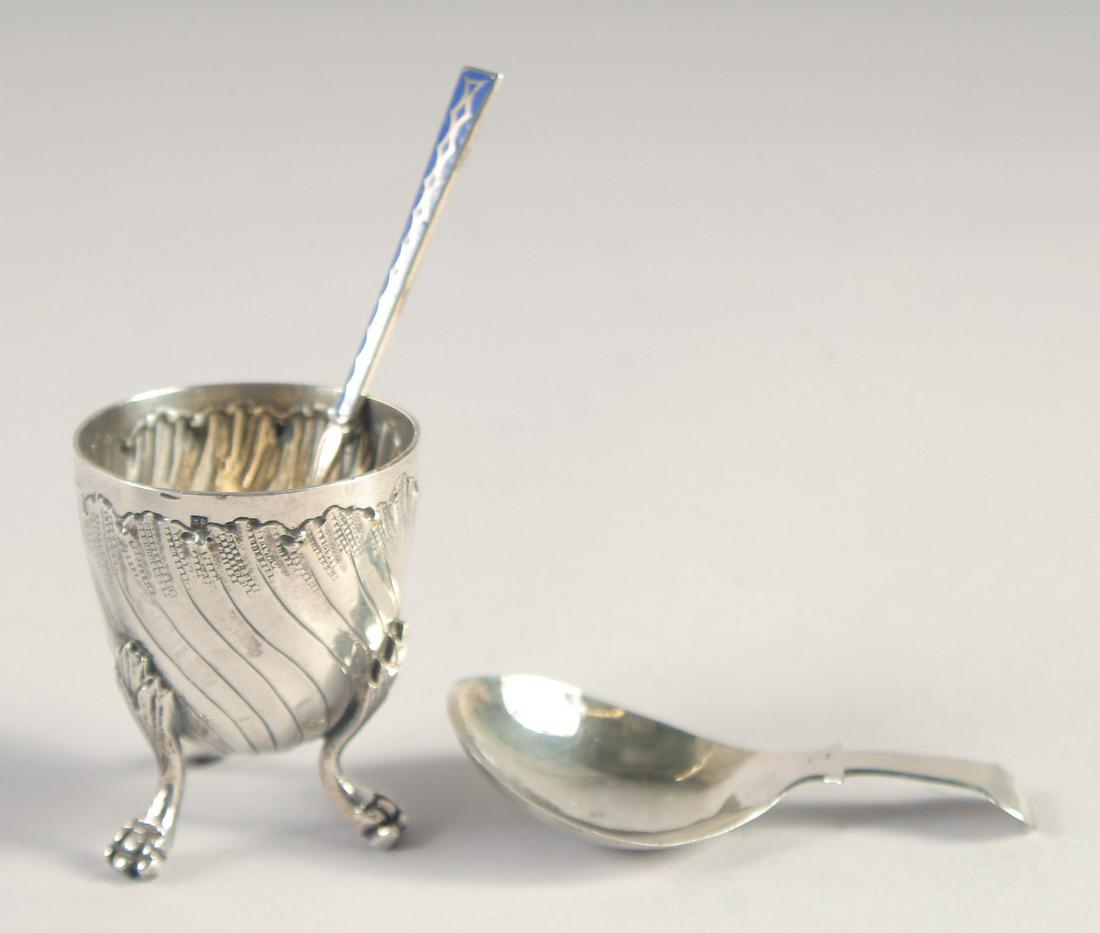 A SMALL ART NOUVEAU SILVER EGG CUP on three claw feet, blue enamel spoon. George III silver caddy: A SMALL ART NOUVEAU SILVER EGG CUP on three claw feet, blue enamel spoon. George III silver caddy spoon, Birmingham, 1781. (3).