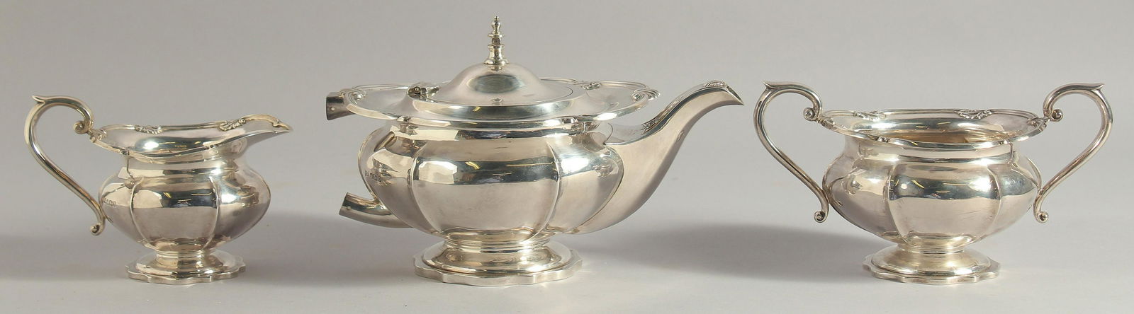 A GEORGE II SILVER THREE PIECE TEA SET, with shell mounts, comprising: tea pot, sugar basin, milk: A GEORGE II SILVER THREE PIECE TEA SET, with shell mounts, comprising: tea pot, sugar basin, milk jug. Sheffield 1931. Weight: approx. 40ozs.