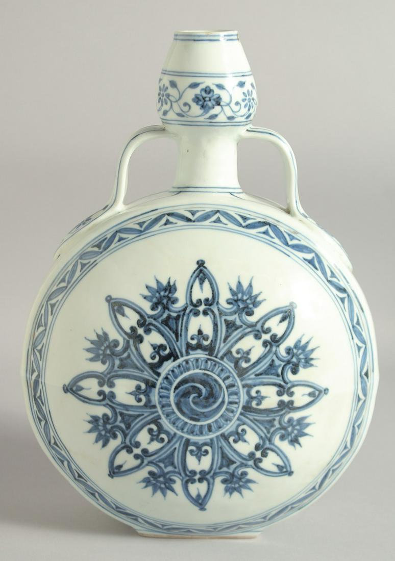A CHINESE BLUE AND WHITE PORCELAIN TWIN HANDLE MOON FLASK, with central yin-yang medallion radiating: A CHINESE BLUE AND WHITE PORCELAIN TWIN HANDLE MOON FLASK, with central yin-yang medallion radiating an eight-pointed starburst with foliate points, 30cm high.
