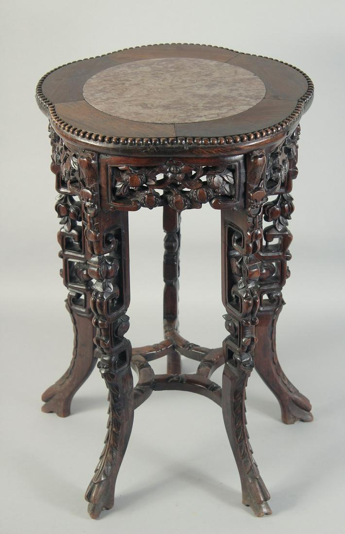 A CHINESE MARBLE INSET CARVED HARDWOOD VASE STAND, with petal-shape top, carved and pierced foliate: A CHINESE MARBLE INSET CARVED HARDWOOD VASE STAND, with petal-shape top, carved and pierced foliate skirt with five similarly carved legs and uniting stretcher, 59cm high, 38.5cm wide.