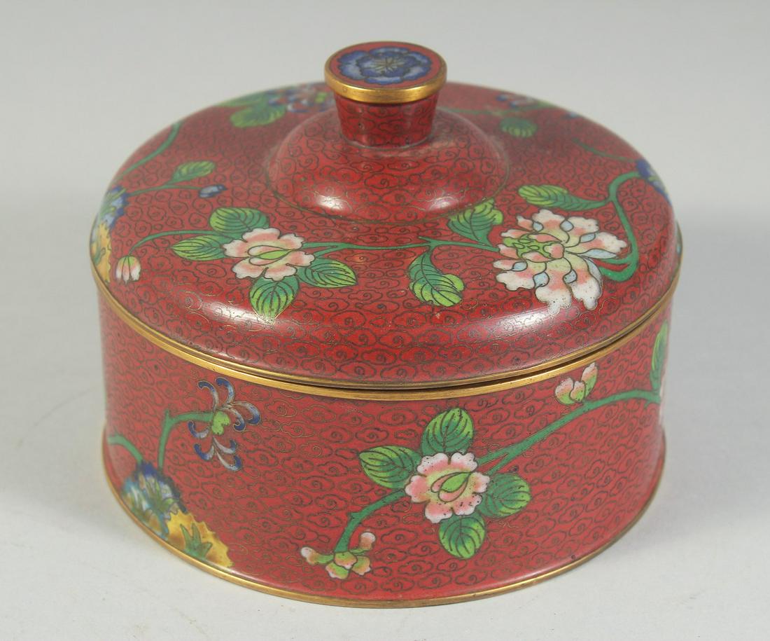 A CHINESE RED GROUND CLOISONNE CIRCULAR BOX AND COVER, decorated with flora, 12.5cm diameter.: A CHINESE RED GROUND CLOISONNE CIRCULAR BOX AND COVER, decorated with flora, 12.5cm diameter.