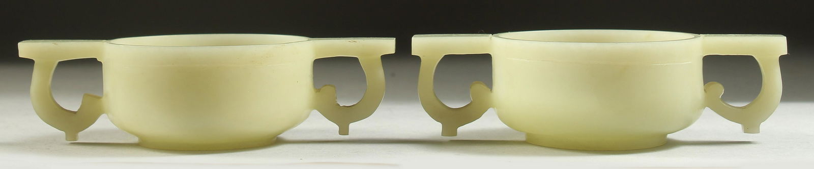 A PAIR OF CHINESE CARVED JADE TWIN HANDLE CUPS, 12cm wide (handle to handle). (1 of 4)