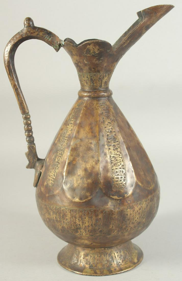 AN ENGRAVED SELJUK STYLE BRASS EWER, with bands of calligraphy, 34.5cm high. (1 of 8)