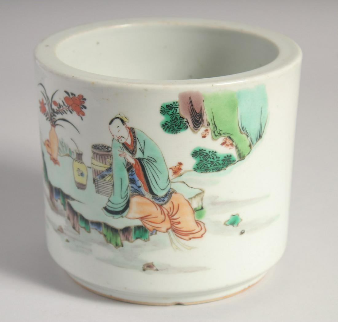 A CHINESE FAMILLE VERTE PORCELAIN BRUSH POT, painted with figures in an outdoor setting, 14cm high.: A CHINESE FAMILLE VERTE PORCELAIN BRUSH POT, painted with figures in an outdoor setting, 14cm high.