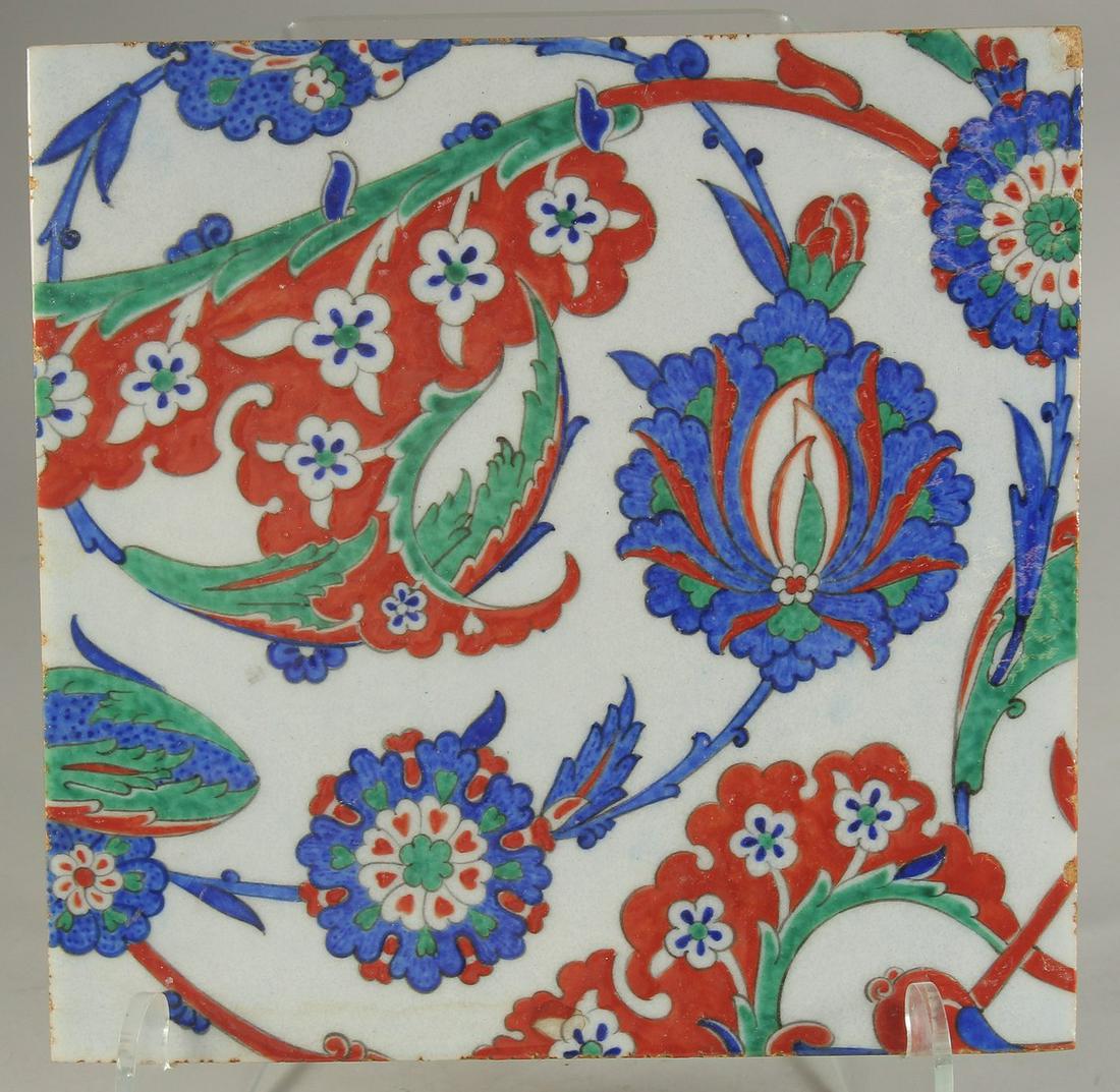 A LARGE IZNIK STYLE GLAZED POTTERY TILE, painted with foliate decoration, 28cm square. (1 of 2)