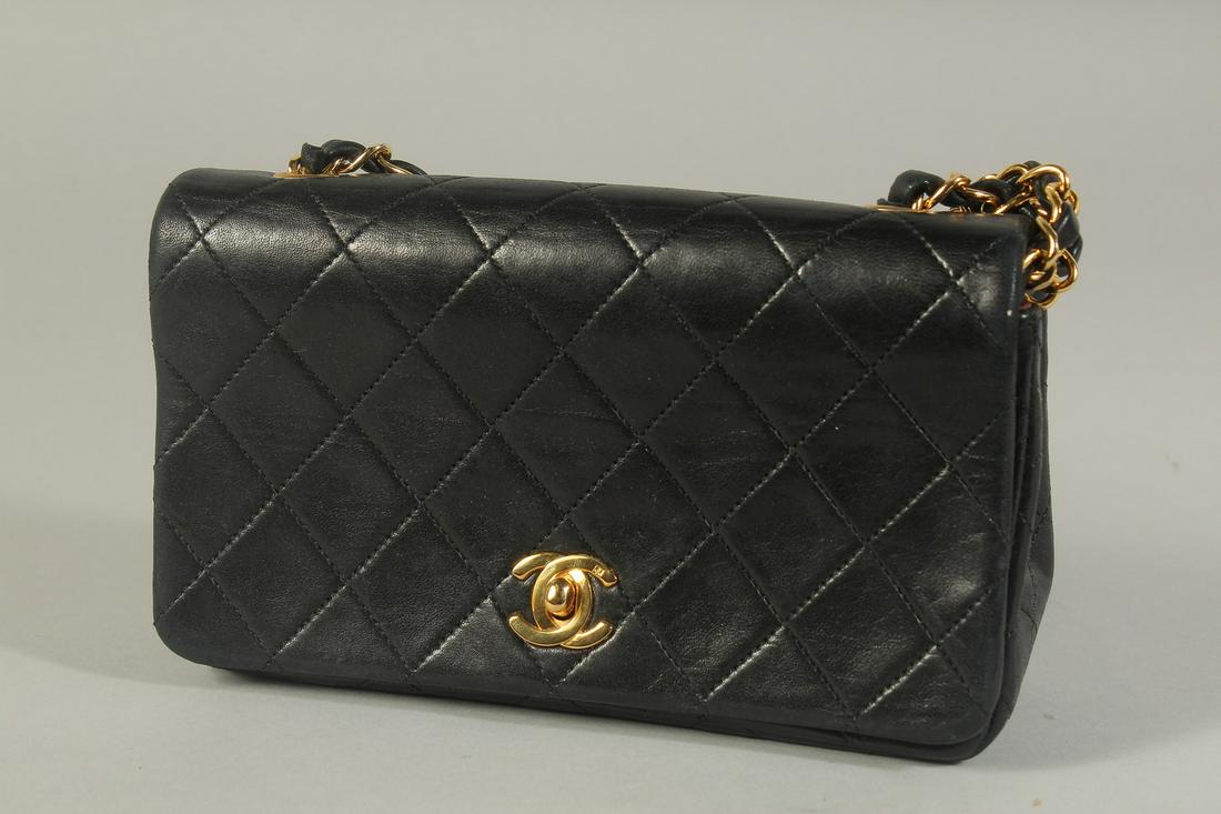 A CHANEL BLACK PADDED LEATHER SHOULDER BAG with long gilt metal and leather entwined strap.  20ins (1 of 5)