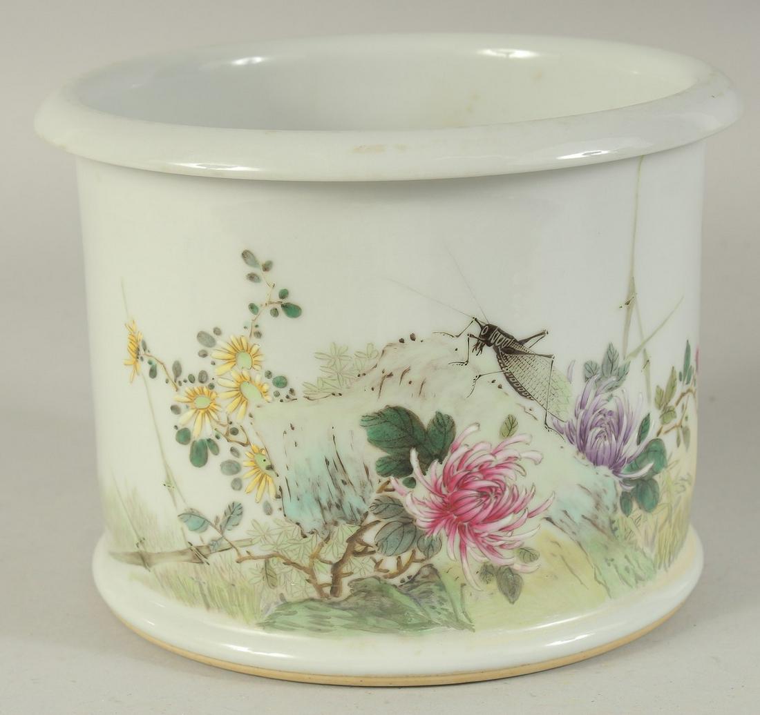 A CHINESE FAMILLE ROSE PORCELAIN BRUSH POT, painted with a cricket and flora, the base with red: A CHINESE FAMILLE ROSE PORCELAIN BRUSH POT, painted with a cricket and flora, the base with red character mark, (restoration), 20.5cm diameter.