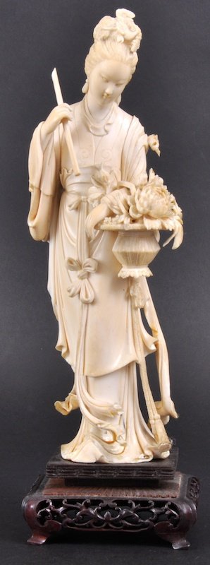 A 19TH CENTURY CHINESE CARVED IVORY FIGURE OF GUAN: A 19TH CENTURY CHINESE CARVED IVORY FIGURE OF GUANYIN modelled holding a basket of flowers, wearing flowing robes, upon a pierced hardwood base. Few losses. 9. 75ins high.