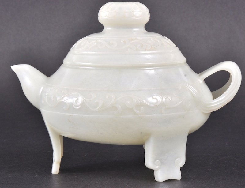 A LATE 19TH/20TH CENTURY CHINESE WHITE JADE CARVED: A LATE 19TH/20TH CENTURY CHINESE WHITE JADE CARVED TEAPOT AND COVER carved with organic foliage, the handle of naturalistic form, upon splayed feet. Good condition. 7ins wide.