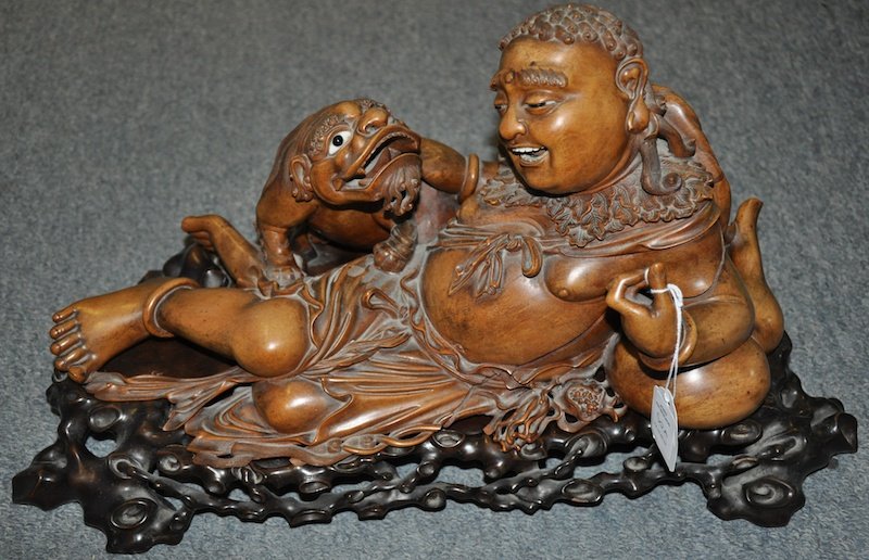 A GOOD 19TH CENTURY JAPANESE HARDWOOD FIGURE OF A : A GOOD 19TH CENTURY JAPANESE HARDWOOD FIGURE OF A RECLINING BUDDAH modelled upon a well carved hardwood base. 13. 5ins wide.