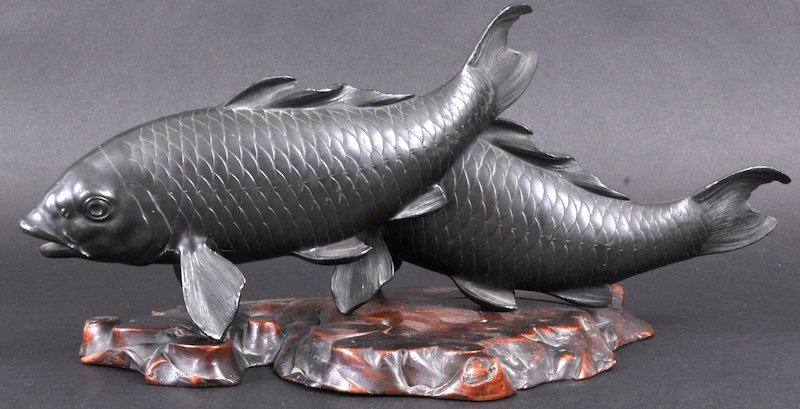 AN EARLY 20TH CENTURY JAPANESE MEIJI PERIOD SPELTE: AN EARLY 20TH CENTURY JAPANESE MEIJI PERIOD SPELTER FIGURE depicting a pair of carp, upon a knurled hardwood base. Signed. 15ins wide.