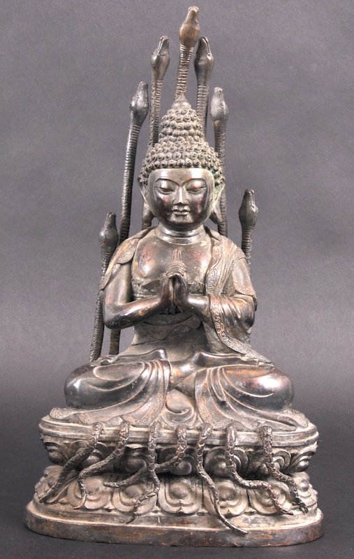 A 19TH/20TH CENTURY CHINESE BRONZE FIGURE OF A BU: A 19TH/20TH CENTURY CHINESE BRONZE FIGURE OF A BUDDAH modelled seated wearing incised robes, upon a base entwined with serpents. Some wear. 12. 5ins high.