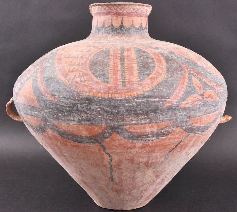 AN EARLY CHINESE LATE NEOLITHIC PERIOD TERRACOTTA: AN EARLY CHINESE LATE NEOLITHIC PERIOD TERRACOTTA VASE with twin handles, decorated upon a rust ground with black and red angular motifs, encased within a floral type design. Loss to handle, nicks to 