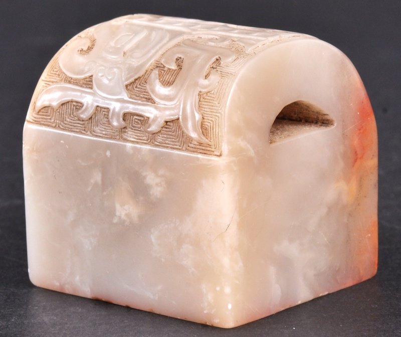 A FINE 19TH CENTURY CHINESE WHITE CELADON JADE SE: A FINE 19TH CENTURY CHINESE WHITE CELADON JADE SEAL well carved to the top with archaic mask heads and motifs, the body decorated with calligraphy. Signed. Good condition. 1. 5ins wide.