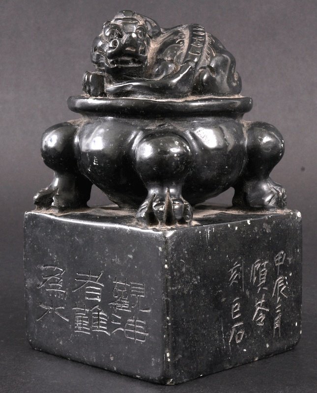 A GOOD 19TH CENTURY CHINESE CARVED GREEN HARDSTON: A GOOD 19TH CENTURY CHINESE CARVED GREEN HARDSTONE DRAGON SEAL the terminal formed as a coiled dragon upon a figural base, the square body incised with calligraphy. Minor nicks. 5. 5ins high.