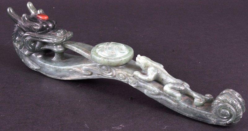 A LARGE CHINESE CARVED JADE BUCKLE as a dragon with: A LARGE CHINESE CARVED JADE BUCKLE as a dragon with tongue after a lizard. 12ins long.