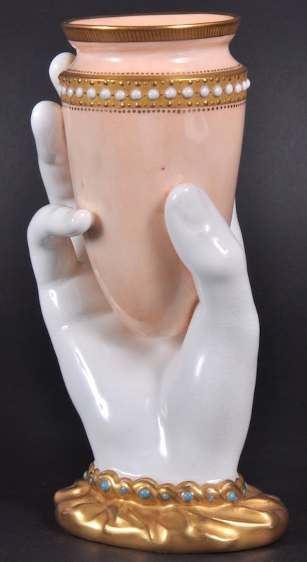 A ROYAL WORCESTER VASE formed as a white hand hold: A ROYAL WORCESTER VASE formed as a white hand holding a seed pearl decorated urn. Blue and Printed Mark. 6ins high.