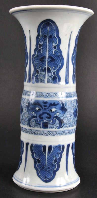 A LOVELY CHINESE KANGXI PORCELAIN BLUE AND WHITE G: A LOVELY CHINESE KANGXI PORCELAIN BLUE AND WHITE GU SHAPED VASE C1690 painted with mask heads and sprayed foliage. Good rim restoration.8.75ins high.