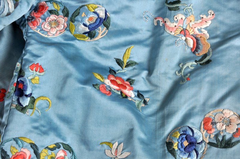 AN EARLY 20TH CENTURY CHINESE SILK JACKET with f: AN EARLY 20TH CENTURY CHINESE SILK JACKET with fur interior, decorated with floral motifs and birds. Minor losses.