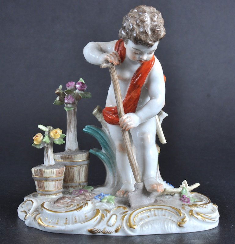 A MEISSEN GROUP OF A YOUNG CUPID GARDENER with a: A MEISSEN GROUP OF A YOUNG CUPID GARDENER with a spade, plants in pots by his side. Cross swords mark in blue, incised number C100, 5ins wide.