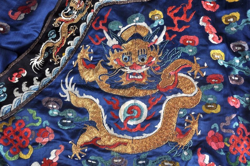 A LATE 19TH CENTURY CHINESE BLUE GROUND DRAGON ROB: A LATE 19TH CENTURY CHINESE BLUE GROUND DRAGON ROBE decorated with five claw dragons amongst clouds and motifs. Minor faults.