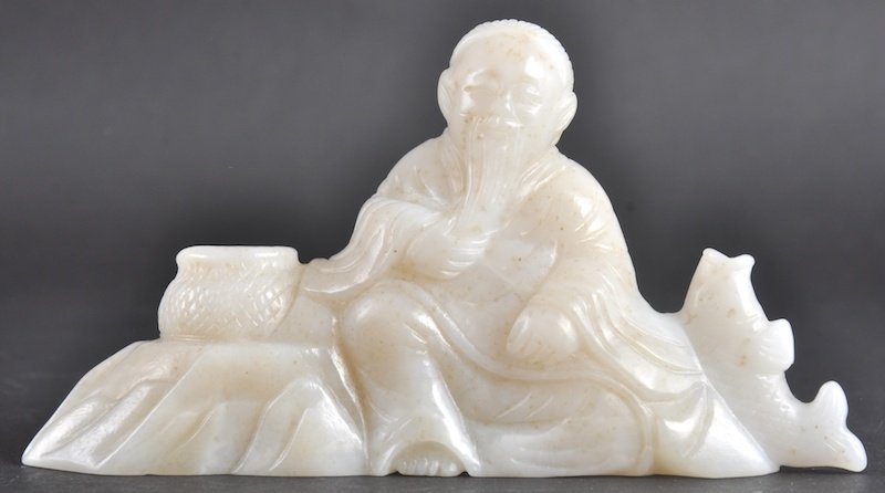 A CHINESE CARVED WHITE RUSSET JADE FIGURAL GROUP d: A CHINESE CARVED WHITE RUSSET JADE FIGURAL GROUP depicting a seated scholar holding a fish. Natural inclusions. 4. 75ins wide.