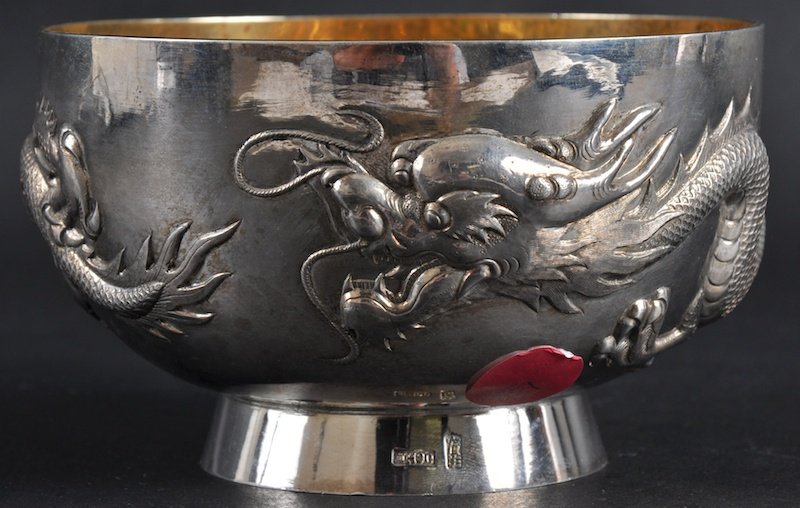 A 19TH CENTURY CHINESE EXPORT SILVER BOWL BY WANG: A 19TH CENTURY CHINESE EXPORT SILVER BOWL BY WANG HING decorated in relief with a dragon in relief. Signed. Good condition. 4. 75ins diameter.