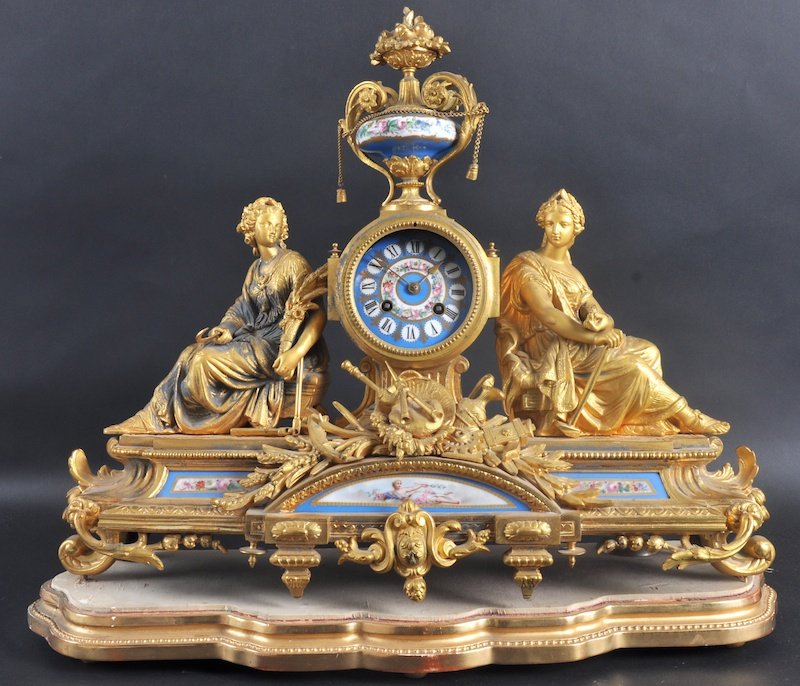 A 19th CENTURY FRENCH ORMOLU CLOCK with painted: A 19th CENTURY FRENCH ORMOLU CLOCK with painted Sevres dial and panel, formed as two classical female figure surmounted by an urn. 21ins wide on a gilt wood base.