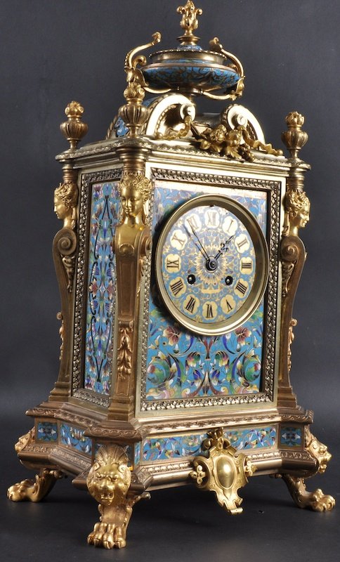A LOVELY 19TH CENTURY FRENCH BRASS AND CHAMPLEVE: A LOVELY 19TH CENTURY FRENCH BRASS AND CHAMPLEVE ENAMEL MANTLE CLOCK with fabulous champlevé panels, eight day movement surmounted by an urn finial. 19ins high.