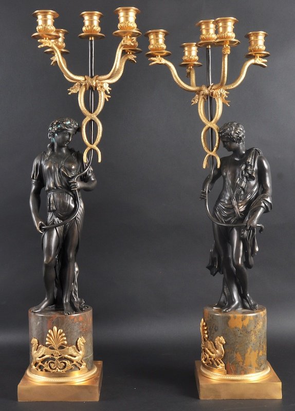 A GOOD PAIR OF REGENCY STYLE BRONZE AND ORMOLU CL: A GOOD PAIR OF REGENCY STYLE BRONZE AND ORMOLU CLASSICAL FIVE LIGHT CANDELABRA formed as a young man and woman holding aloft serpent moulded scrolling branches supported on a circular pedestal. 27ins 