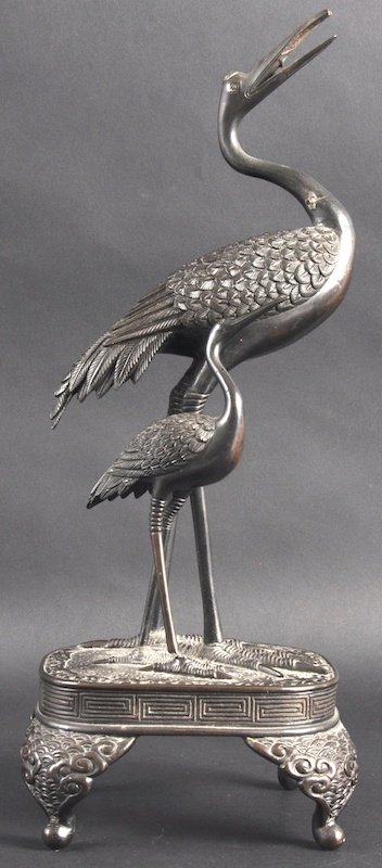 A LATE 19TH CENTURY JAPANESE MEIJI PERIOD BRONZE FI: A LATE 19TH CENTURY JAPANESE MEIJI PERIOD BRONZE FIGURAL GROUP depicting a pair of cranes standing upon a circular base. 16. 5ins high.