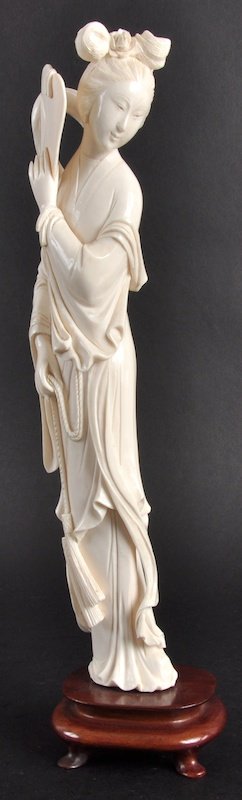 AN EARLY 20TH CENTURY CHINESE IVORY FIGURE OF GUA: AN EARLY 20TH CENTURY CHINESE IVORY FIGURE OF GUANYIN modelled holding a fan in one hand, upon a hardwood base. Good condition. Ivory 11. 75ins high.