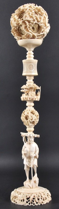 A 19TH CENTURY CHINESE CANTON IVORY PUZZLE BALL O: A 19TH CENTURY CHINESE CANTON IVORY PUZZLE BALL ON STAND Qing, carved as a buddhistic figure standing upon a base carved with dragons. Minor faults. 1ft 7. 5ins high.