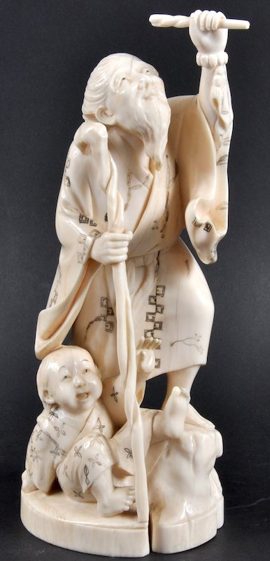 AN EARLY 20TH CENTURY JAPANESE MEIJI PERIOD OKIMON: AN EARLY 20TH CENTURY JAPANESE MEIJI PERIOD OKIMONO depicting a male holding a staff with a young child. Signed. Good condition. 8. 75ins high.