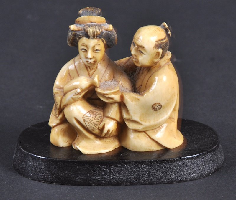 A CARVED IVORY NETSUKE OF A MAN AND WOMAN TAKING T: A CARVED IVORY NETSUKE OF A MAN AND WOMAN TAKING TEA.