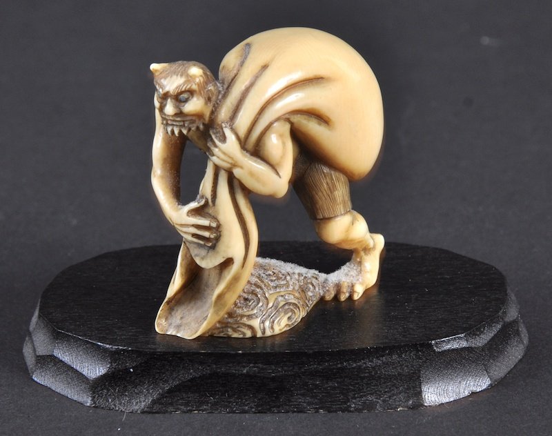 A CARVED IVORY NETSUKE OF A CAT BURGLAR. : A CARVED IVORY NETSUKE OF A CAT BURGLAR.