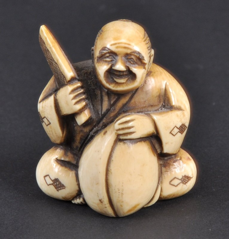 A CARVED IVORY NETSUKE OF A MAN WITH A CHOPPER. : A CARVED IVORY NETSUKE OF A MAN WITH A CHOPPER.