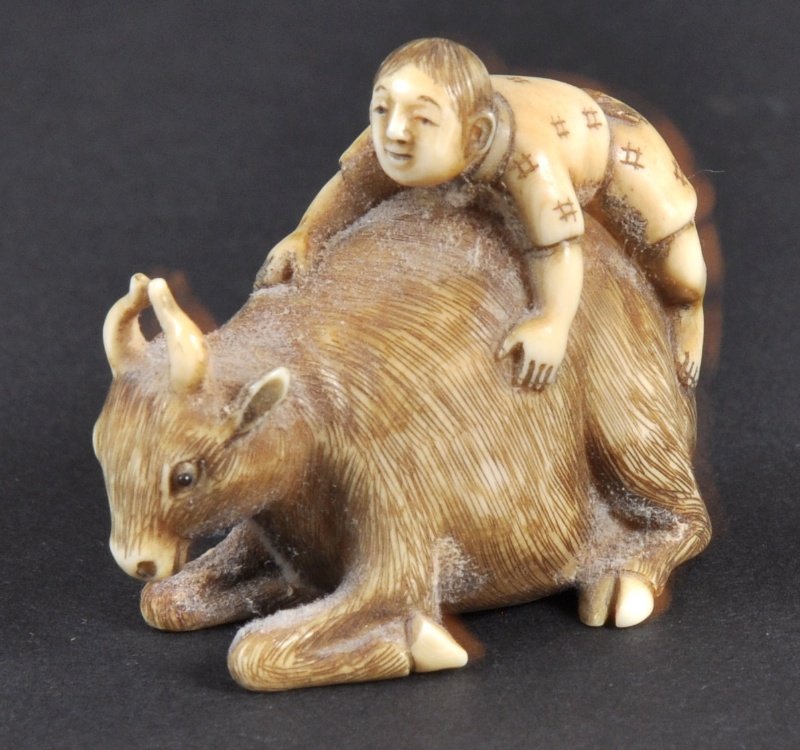 A CARVED IVORY NETSUKE OF A MAN RIDING AN OX. : A CARVED IVORY NETSUKE OF A MAN RIDING AN OX.
