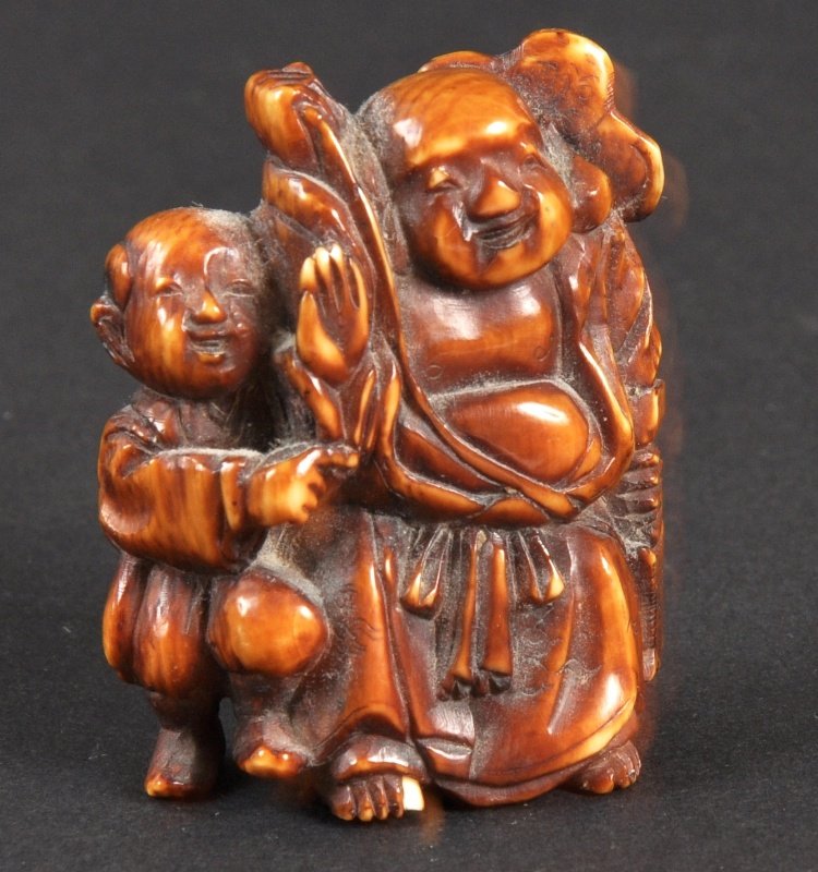 A CARVED IVORY NETSUKE OF A MAN WITH A YOUNG CHILD: A CARVED IVORY NETSUKE OF A MAN WITH A YOUNG CHILD.