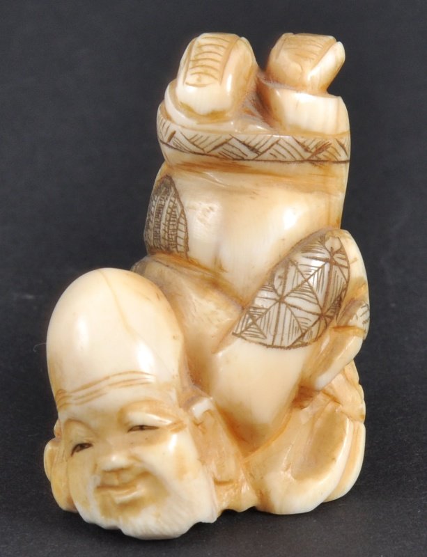 A CARVED IVORY NETSUKE OF AN ACROBAT. : A CARVED IVORY NETSUKE OF AN ACROBAT.