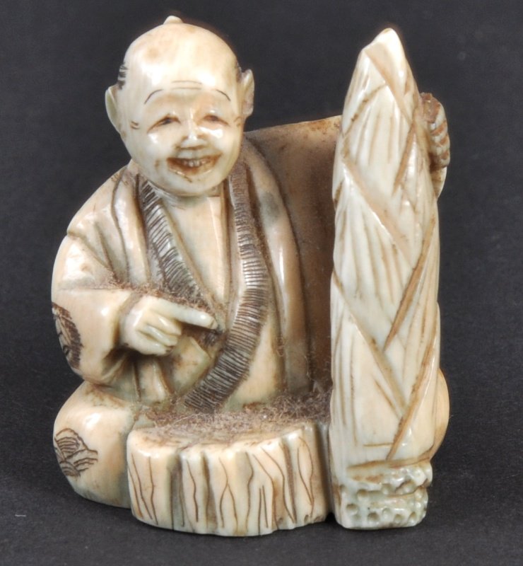 A CARVED IVORY NETSUKE OF A SEATED MAN. : A CARVED IVORY NETSUKE OF A SEATED MAN.